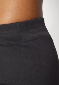 Černé legíny s vysokým pasem, hladkým povrchem a elastickým pasem, se splývavými švy pro elegantní a přiléhavý vzhled.