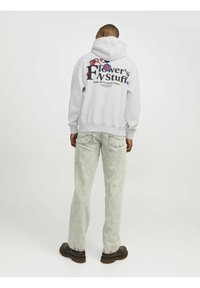 Sweatshirt à capuche gris avec des graphismes colorés et du texte au dos. Assorti à un jean en denim clair et des chaussures noires.