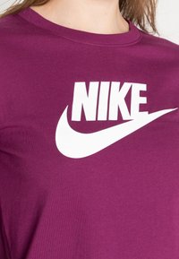 Lila bomull T-shirt med en stor vit Nike-logotyp över bröstet. Enkel design med rundad hals och slät textur utan mönster.