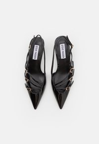 Décolleté in pelle patent nera con punta affilata, caratterizzate da accenti in hardware dorato e fascette incrociate sulla parte frontale.