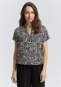 Blusa nera a maniche corte con motivo astratto bianco e beige, senza colletto, dal fit rilassato e realizzata in un tessuto leggero.