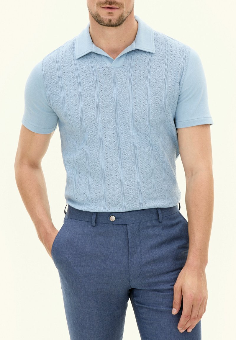 Polo bleu clair à manches courtes avec un motif texturé et un col classique, associé à un pantalon tailleur bleu foncé avec un bouton.