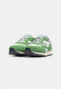 Green sneakers featuring a combination of textured suede and mesh, with white accents, a padded collar, and a black rubber sole.