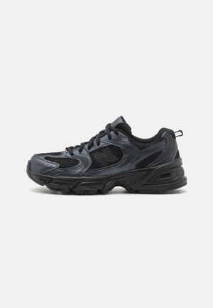 Baskets athlétiques gris foncé et noir avec panneaux en mesh, lacets et une semelle robuste conçues pour la course ou la marche.