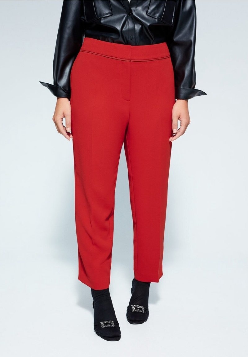Rode op maat gemaakte broek met een rechte pasvorm, gladde stof en zijzakken. Gecombineerd met zwarte gestructureerde schoenen met een decoratieve gesp.