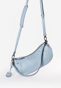 Borsa a spalla in pelle azzurro chiaro con forma curva, superficie texturizzata, chiusura con zip e tracolla regolabile con dettagli in metallo nero.