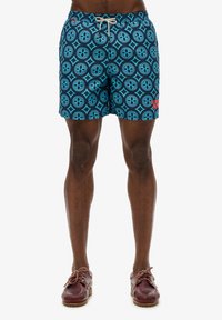 Zwemshorts in het blauw met een herhalend patroon van cirkels en diamanten. Voorzien van een elastische tailleband met aantrekkoord en zijzakken.