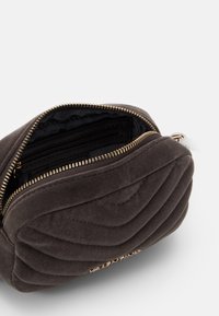 Prošívaná tmavě šedá taštička se zipem. Měkká textura, obsahuje vnitřní kapsy a kovové doplňky se zlatým tónem.