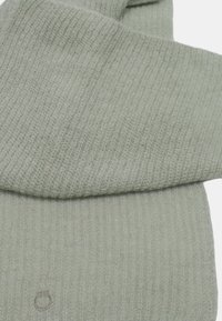 Scarf di maglia verde chiaro con texture a coste, caratterizzato da un design piegato e un piccolo logo in rilievo vicino al bordo inferiore.
