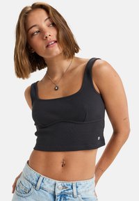 Čierny rebrovaný crop top so širokými popruhmi a štvorcovým výstrihom, ktorý sa vyznačuje detailným švom a malým logom na leme.