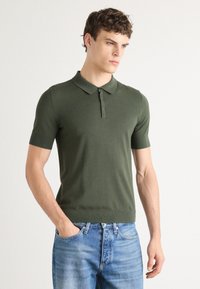 Kortermet olivengrønn polo-skjorte med krage og figursydd design, laget av myk, teksturert stoff.