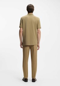 Khaki polo z gładkiej tkaniny oraz dopasowane spodnie. Strój ma krótkie rękawy, klasyczny kołnierzyk i prosty krój spodni.