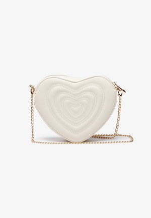 Biała torebka w kształcie serca z pikowanym przeszyciem, złotym łańcuszkowym paskiem, gładką teksturą oraz subtelnym, warstwowym wzorem serca na przodzie.