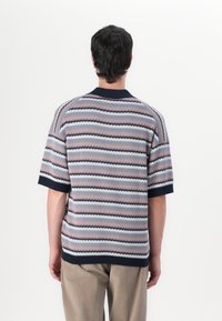 Kurzärmeliger Strickpullover mit einem wellenförmigen Streifenmuster in Pastellfarben, mit einem marinefarbenen Kragen und einem gerippten Saum. Strukturiertes Gewebe.