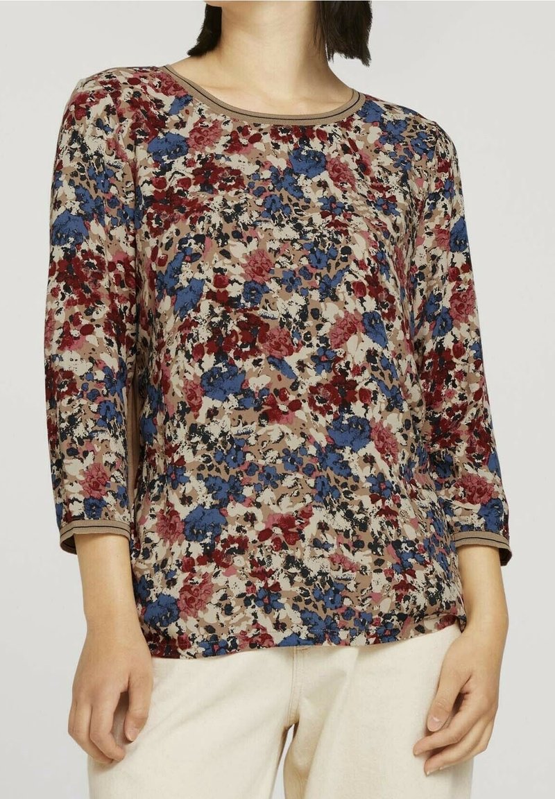 Blommönstrad topp i brunt, med blå, röd och beige ton. Rund halsringning med kontrasterande kant och trekvartslånga ärmar. Mjuk tyg.
