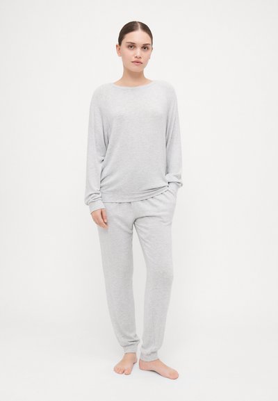 Conjunto de roupa de casa cinza composto por uma blusa de manga longa com decote redondo e corte descontraído, emparelhada com calças tapered coordenadas com punhos.