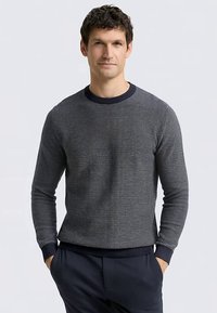 Pull texturé bleu marine avec un col rond et des poignets côtelés, fabriqué dans un matériau doux, présentant un motif subtil sur toute la surface.