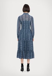 Rochie albastră cu mâneci lungi, cu imprimeu de șarpe, având un bust ajustat și o fustă stratificată. Fabricată dintr-un material transparent cu un finisaj texturat.
