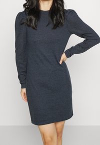 Ciemnod granatowa sukienka z długim rękawem, wykonana z miękkiego materiału, o dopasowanym kroju, z bufkami na rękawach i okrągłym dekoltem.