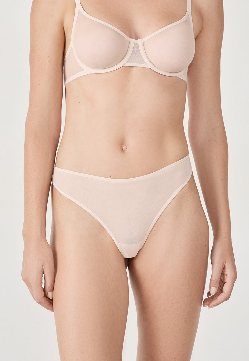 Reggiseno rosa chiaro e perizoma abbinato, realizzati in materiale a rete trasparente. Il design presenta una finitura liscia con bande in contrasto.