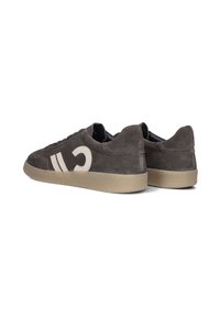 Brown suede sneakers with beige rubber soles, featuring a distinct white logo and two white stripes on the side. Low-top design, lace-up style.