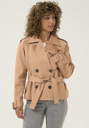 Vaaleanbeige kaksirivinen trench coat, jossa on solmittava vyötärö, hartialäppä ja mustat napit. Sileä kangas ja muotoiltu istuvuus.