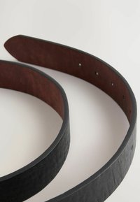Schwarzer Ledergürtel mit strukturiertem Äußeren und glattem Inneren, mit einer gebogenen Form und mehreren Löchern zur Verstellbarkeit.