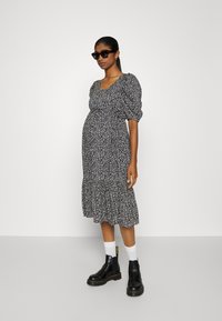 Vestuário midi floral em preto e branco com mangas bufantes e bainha rodada, combinado com botas ankle pretas e meias brancas.