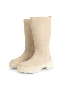 Hoge beige suède laarzen met stevige crèmekleurige rubberen zolen en ronde neuzen, zij aan zij weergegeven op een witte achtergrond.