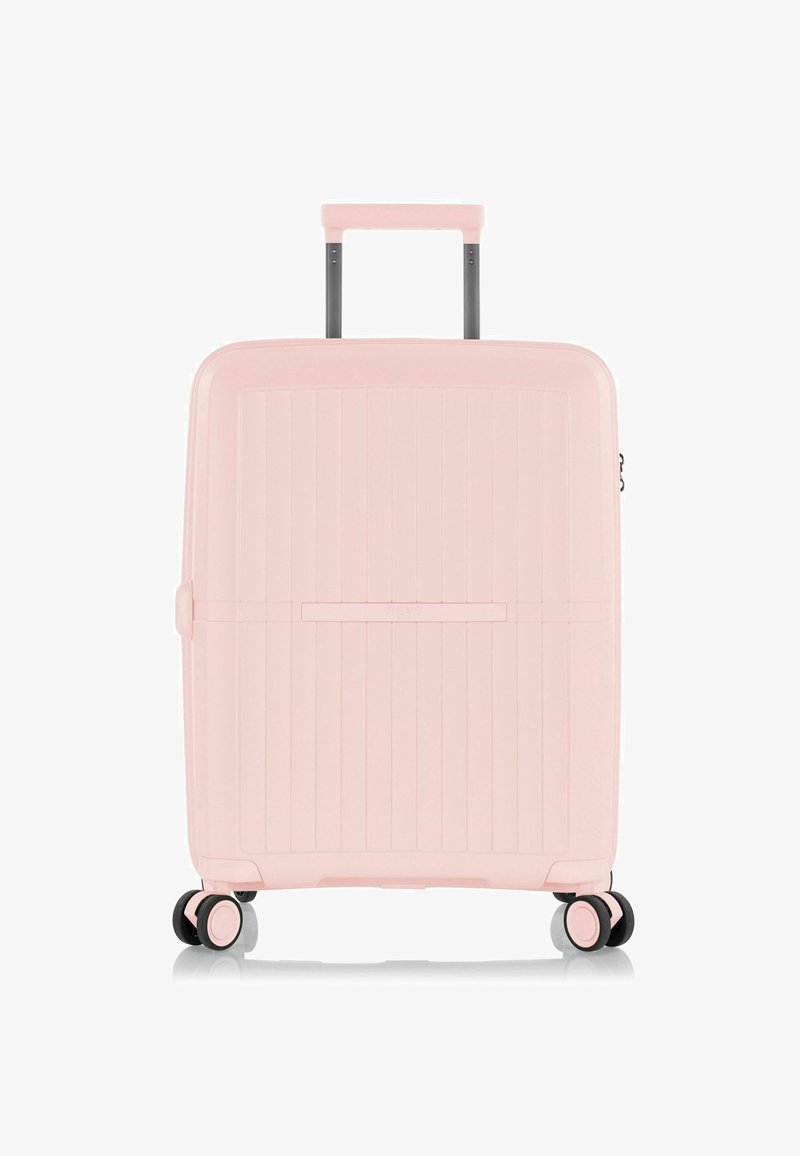 Maleta de hard-shell en rosa pastel, de forma rectangular, con textura estriada vertical, mango retráctil y cuatro ruedas para una mayor movilidad.