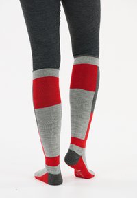 Kniestrümpfe mit einem Muster aus roten und grauen Blocken, hergestellt aus einem weichen, dehnbaren Material mit geripptem oberen Rand und kontrastierenden Fersen- und Zehenakzenten.