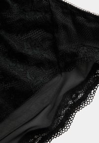Zwarte kant lingerie met bloemmotieven, een gladde mesh voering, verfijnde scalloped randen en ingewikkelde kantdetails.