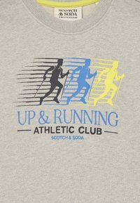 Tres siluetas de figuras corriendo con bastones en negro, azul y amarillo sobre el texto "UP & RUNNING ATHLETIC CLUB" en una tela gris.