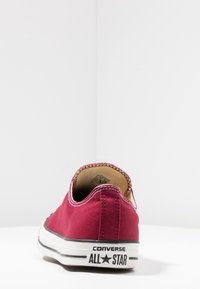 Czerwone płótno niskie tenisówki z białą gumową podeszwą i charakterystycznym czarno-białym logo "CONVERSE ALL STAR" na pięcie. Teksturowana wykończenie materiału.