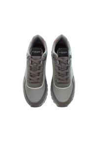 Šedé tenisky U.S. Polo Assn. se šňůrkami, černou značkovou štítkem na jazyku a gumovými podrážkami, zobrazené z vrchního pohledu na bílém pozadí.