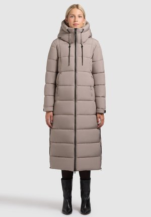 Gaiši bēša gara pūdera jaka ar kapuci, kas aprīkota ar vertikālām vīstjernu ribām, priekšējām rāvējslēdzējām un regulējamām aukliņām.