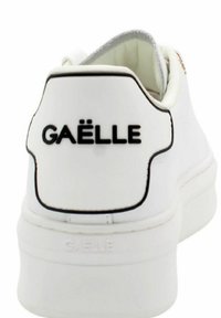 Sneaker bianco con una superficie liscia e texture. Presenta un logo nero "GAËLLE" sul tallone con un contorno nero a contrasto. Design minimalista.
