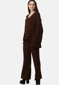 Ensemble en tricot côtelé marron, composé d'un cardigan à boutons avec un col en V et des manches larges, associé à un pantalon à jambe droite.