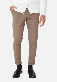 Chinos marroni chiari con vestibilità slim, orli arrotolati e una texture di cotone liscia. Abbinati a mocassini neri e calzini scuri.