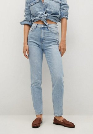 Vaqueros de tiro alto de mezclilla en azul claro, con un corte ajustado y un sutil desgaste. Combinados con mocasines de cuero marrón.