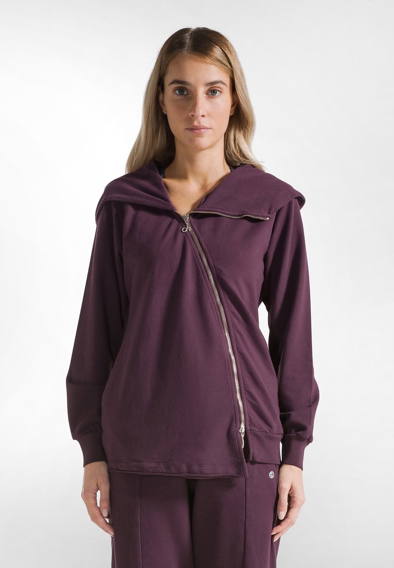 Felpa con zip viola a vestibilità rilassata, con cappuccio oversize e maniche lunghe. Presenta una zip diagonale e un morbido materiale in cotone.