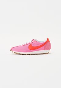 Nike löparskor med en rosa nätovandel, orangea mockadetaljer, vita snören och en gummisula med framträdande greppspikar.