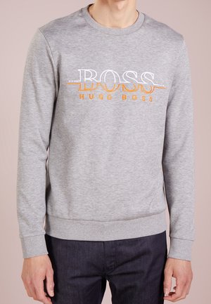 Grå sweatshirt med rund halsringning, långa ärmar och ribbad mudd. Noterbar broderad "BOSS"-logotyp i vitt och orange på bröstet.