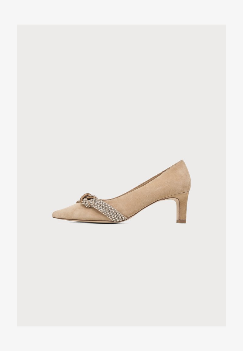 Escarpin beige en daim à talon moyen et bout pointu, avec un nœud décoratif en strass argenté sur la bride avant.