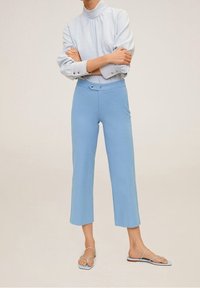 Pantalons courts taille haute bleu clair en tissu doux, associés à un haut bleu clair assorti avec des détails plissés et des accents de boutons.