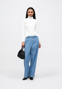 Λευκό εφαρμοστό ζιβάγκο, ανοιχτό μπλε φαρδιές παντελόνες, μαύρη τσάντα χεριού και μαύρες block heels. Λείος καμβάς, χαλαρή εφαρμογή και μινιμαλιστικός σχεδιασμός.