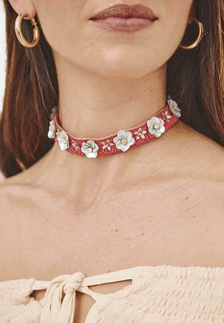 Chocker de tela roja adornado con acentos de flores blancas y rosas, con un acabado texturizado y un diseño simple.