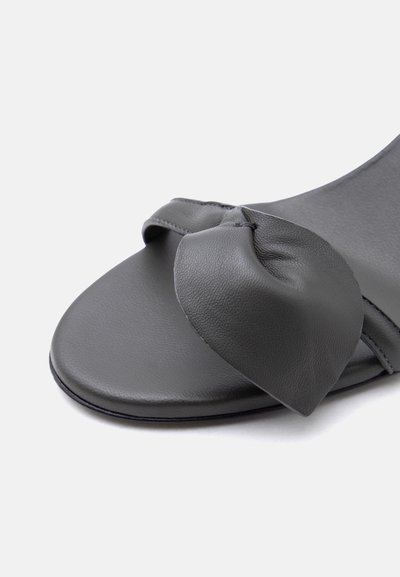 Εμπρός όψη σκούρου γκρι σανδάλου ανοιχτού μπροστά με μεγάλο μαλακό δερμάτινο φιόγκο στη λουρίδα πάνω από τα δάχτυλα.