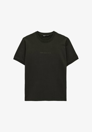 Ciemnozielony t-shirt z krótkim rękawem i okrągłym dekoltem, z subtelnym napisem "OWN YOUR PATH" na środku klatki piersiowej.