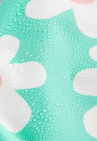 Wasserabweisender Stoff mit mintgrünem Hintergrund, der mit weißen Blumendessins verziert ist und von zahlreichen Wassertropfen für eine texturierte Detailierung bedeckt ist.